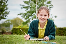 A student writing on a clipboard while smiling