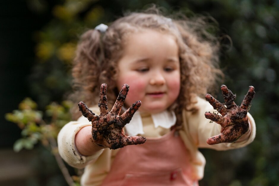 Girl plays outside with muddy hands