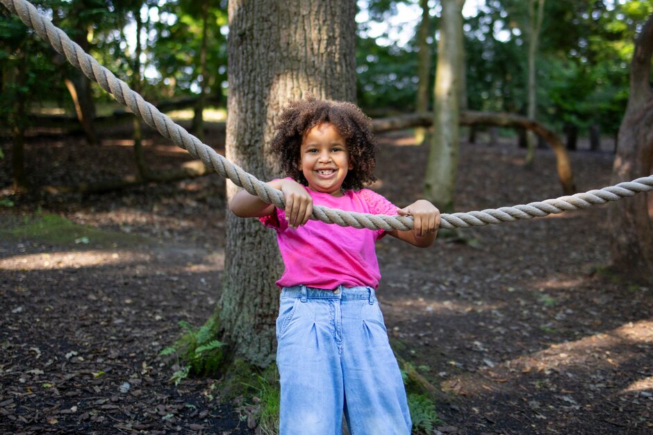Girl playing with rope in woodland area