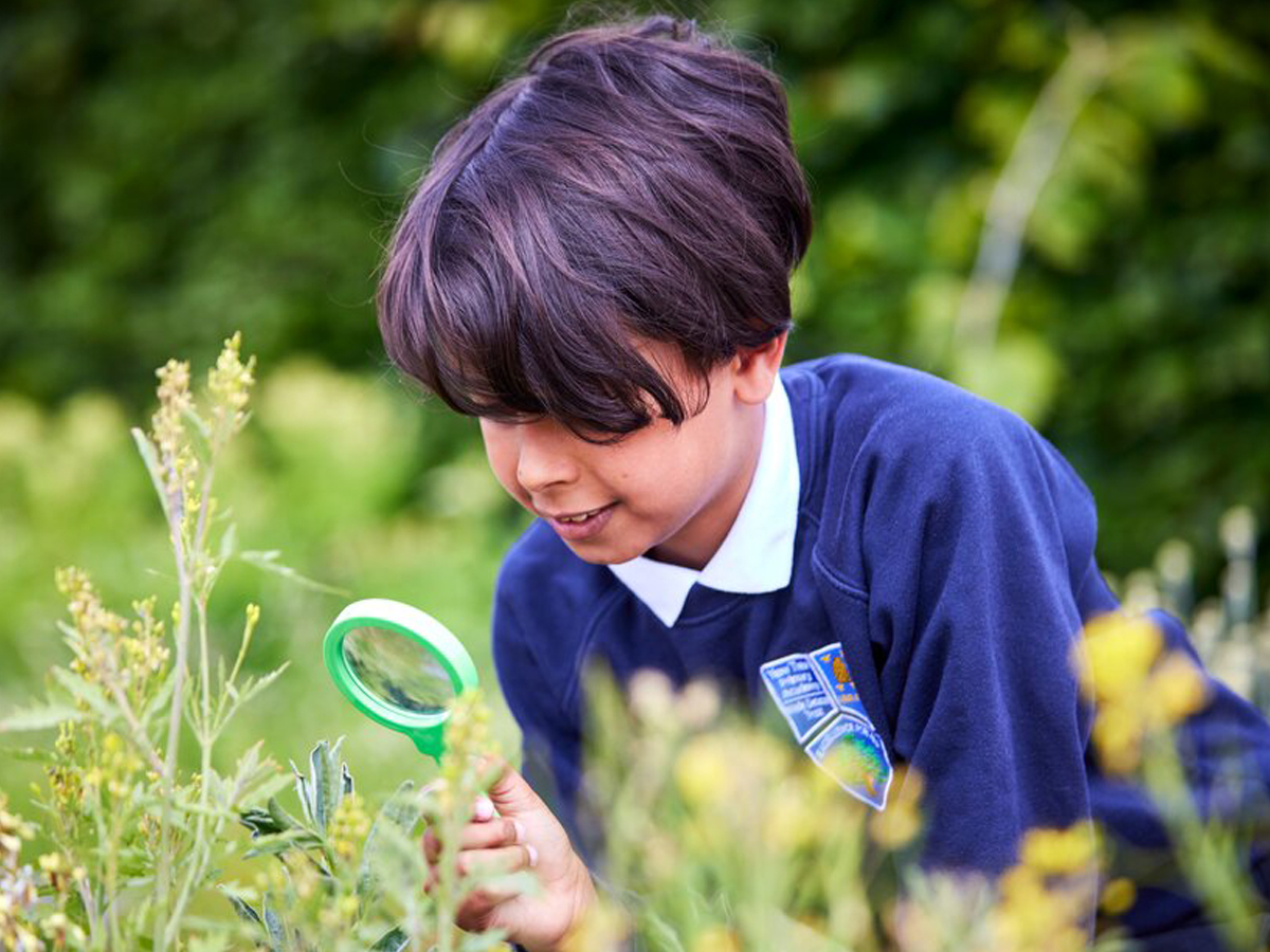 Boy using magnifying glass outside
