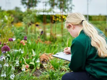 Student sketching flowers on a clipboard
