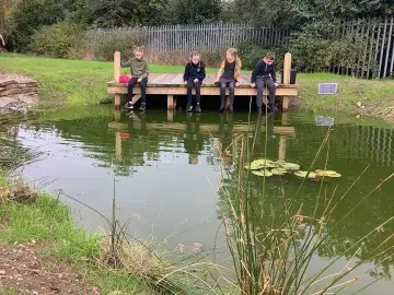 Pupils look into a pond on their school grounds