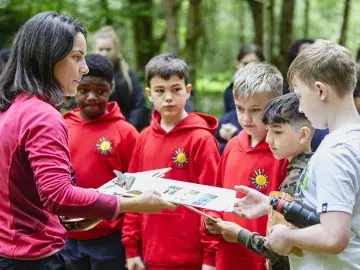 Adult sharing Nature Park education resources with pupils in the outdoors