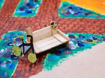 Detail of a handmade model showing a bench, bicycle and flower beds