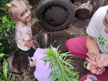 two small children looking under a tyre for insects