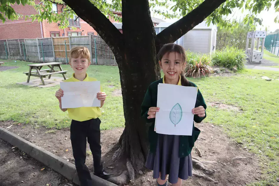 Students holding nature drawings