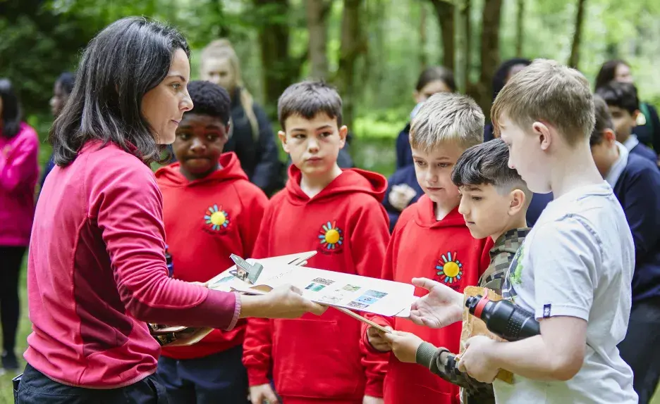 Adult sharing Nature Park education resources with pupils in the outdoors