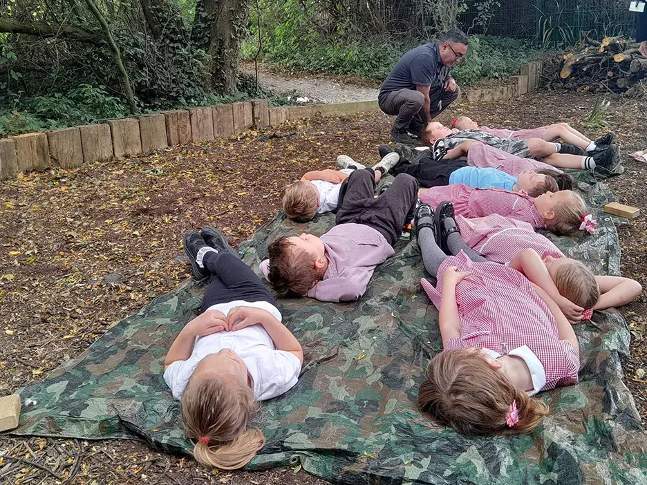 Pupils lying on the ground as part of a forest bathing activity