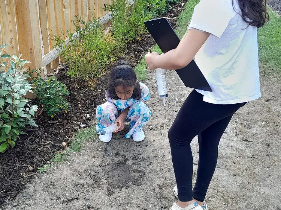 A pupil looks at water on the ground as part of a permeability test